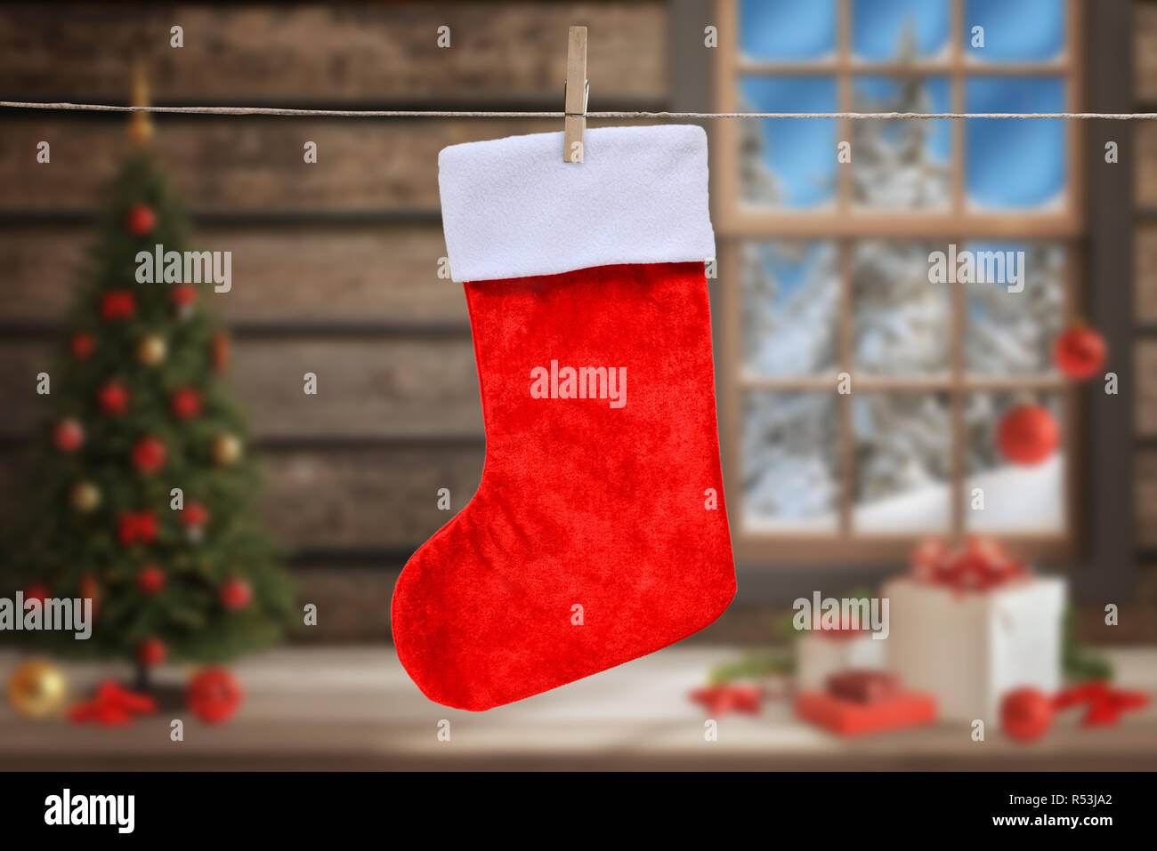 Empty Christmas sock for mockup, greeting text. Christmas tree, gifts and decorations in background. Stock Photo