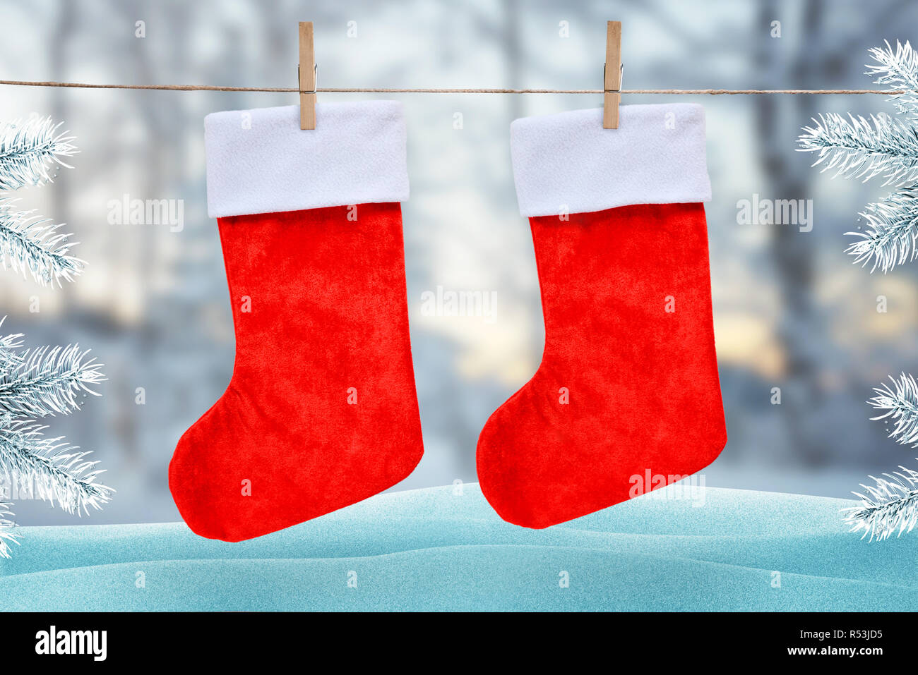 Christmas red socks hooked with a clip on a rope. Winter, snow scene with Christmas tree in background. Stock Photo