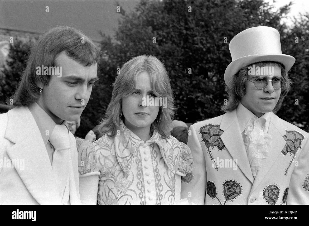 Elton John (right) pictured here as best man to his songwriting partner Bernie Taupin.  Bernie marries 19 year old American student Maxine Feibelman on Saturday 27th March 1971 at  Holy Rood Catholic Church, in Market Rasen, Lincolnshire.  Best man Elton wears a white suit embroided with red and yellow roses, and a white silk top hat. All made in Los Angeles, by the same tailer who has designed suits for Elvis Presley. (Tailer is named in captioned but writing difficult to make out)  Bride Maxine, wears a full length traditional gown in white with old gold irises embroided on the bodice.  Groo Stock Photo
