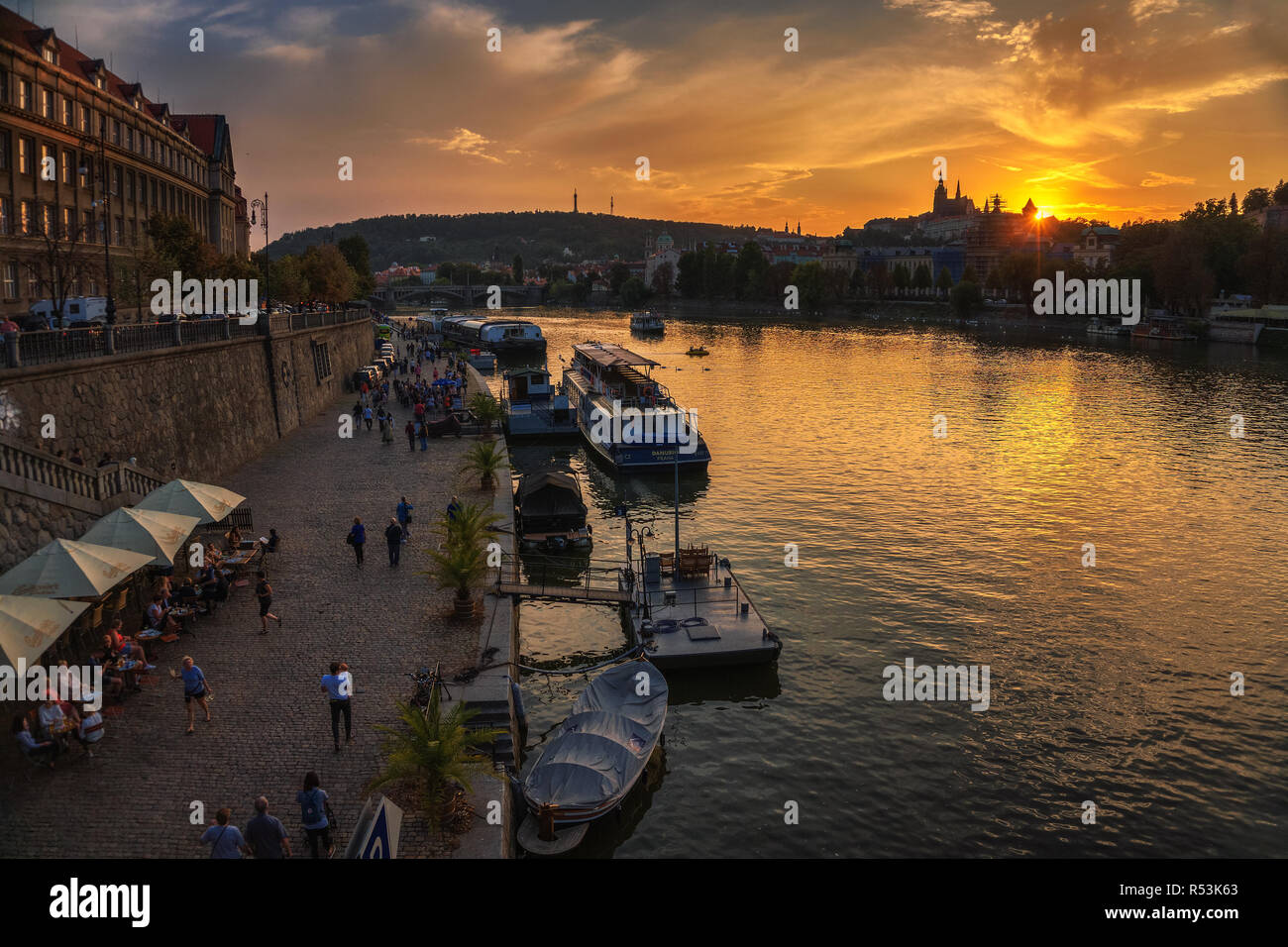 People walk along the Vltava river in Prague at sunset Stock Photo