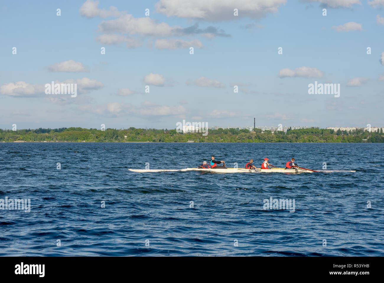 Rowers children with their coach in red life-jacket are rowing white ...