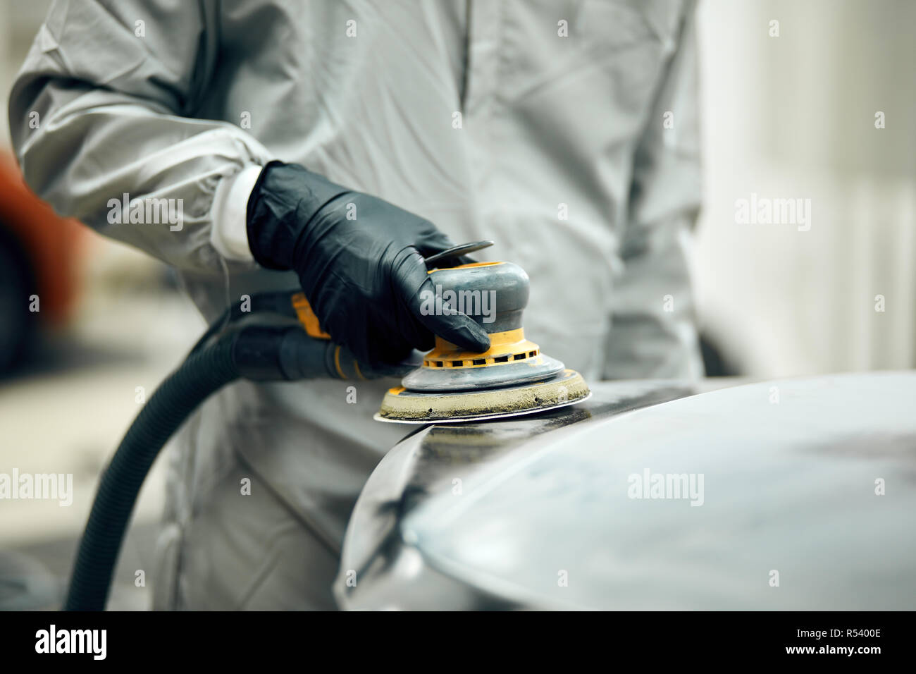 mechanic grinds car part for painting. Car body work auto repair paint after accident Stock Photo