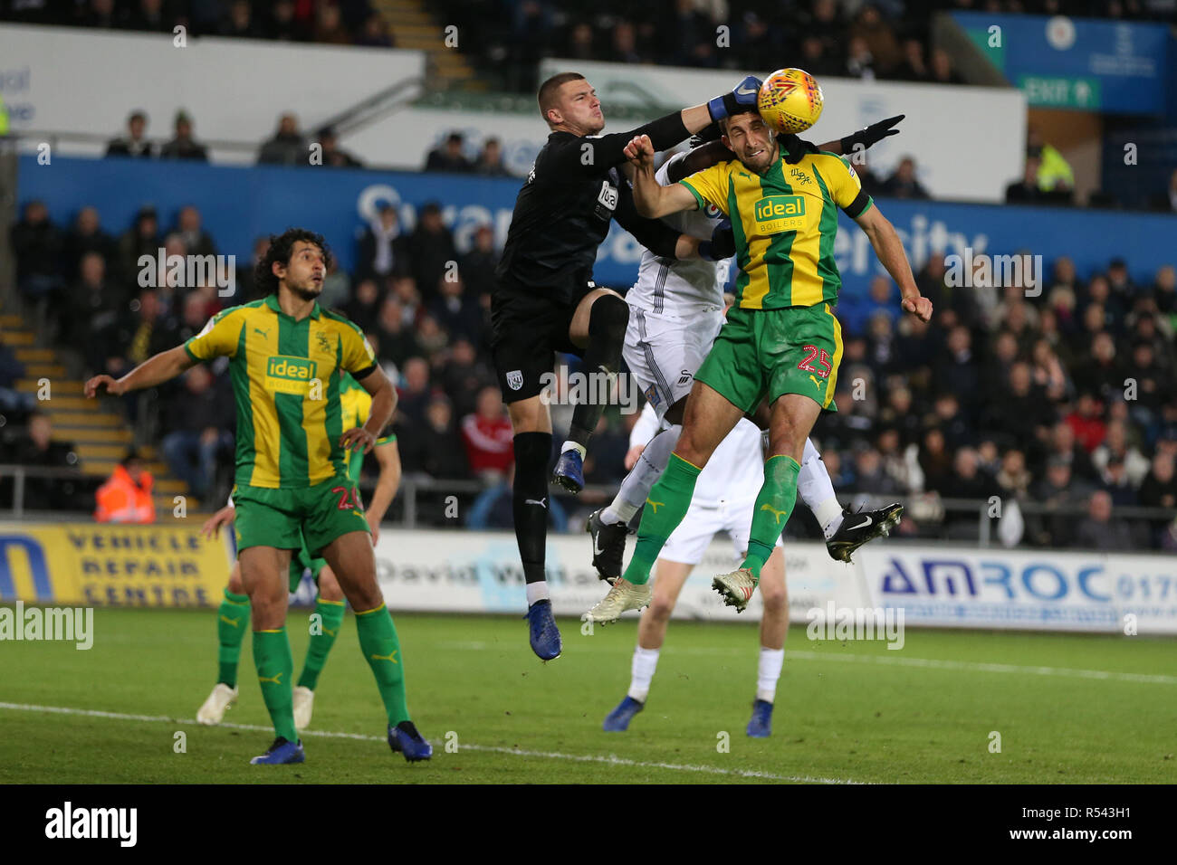 Swansea, Wales, UK. 28th Nov 2018. Sam Johnstone, the goalkeeper of West Bromwich Albion punches clear over Craig Dawson of West Brom and Wilfried Bony of Swansea city. EFL Skybet championship match, Swansea city v West Bromwich Albion at the Liberty Stadium in Swansea, South Wales on Wednesday 28th November 2018. this image may only be used for Editorial purposes. Editorial use only, license required for commercial use. No use in betting, games or a single club/league/player publications. pic by Andrew Orchard/Andrew Orchard sports photography/Alamy Live news Stock Photo