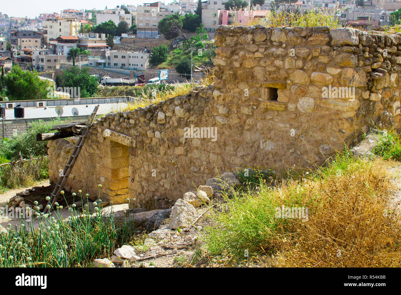 A retro style stone house in the open air museum of Nazareth Village Israel. houses in the modern Nazareth can be seen in the background. This site gi Stock Photo