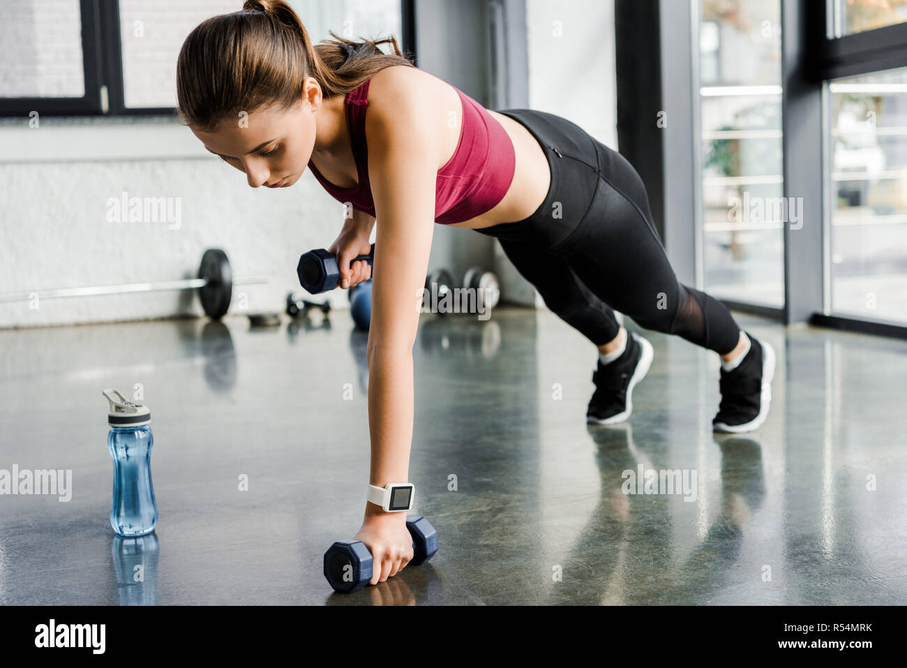 attractive focused sportswoman doing push ups with dumbbells at gym Stock Photo Alamy