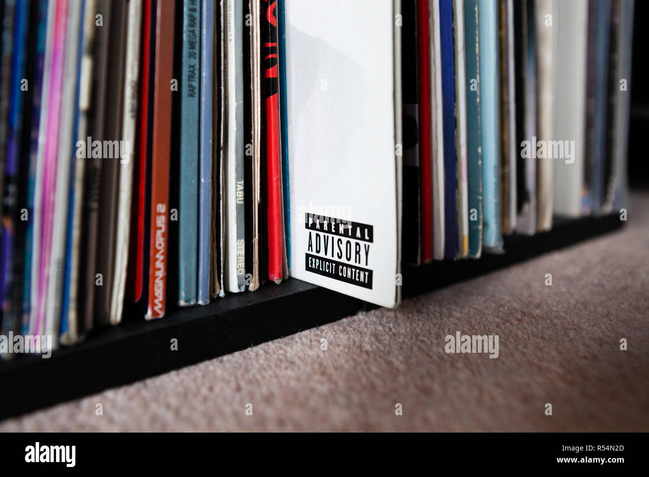 Parental Advisory label on vinyl record sleeve amongst stack of records on shelf Stock Photo