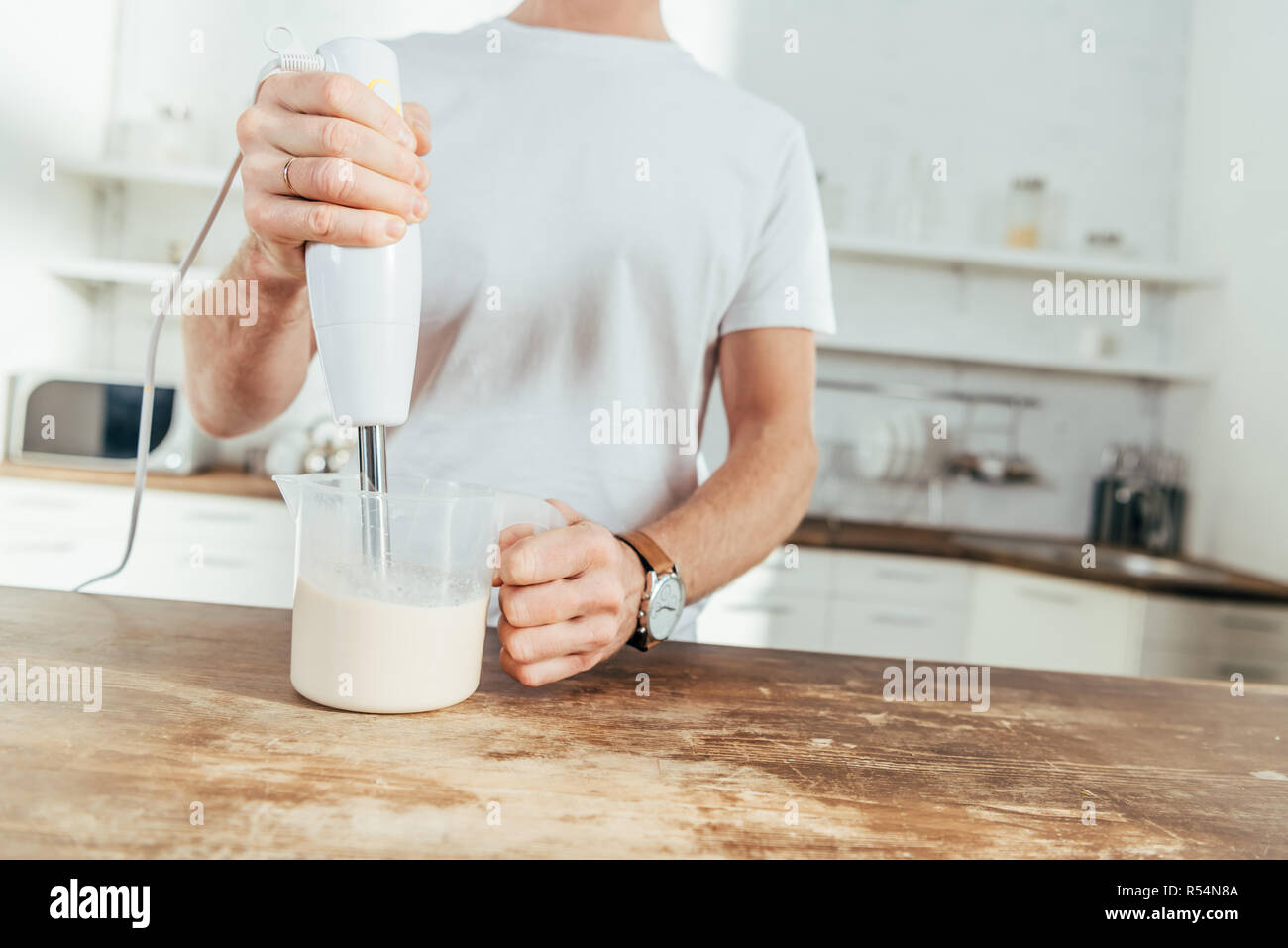 cropped shot of man mixing protein shake with electrical blender at