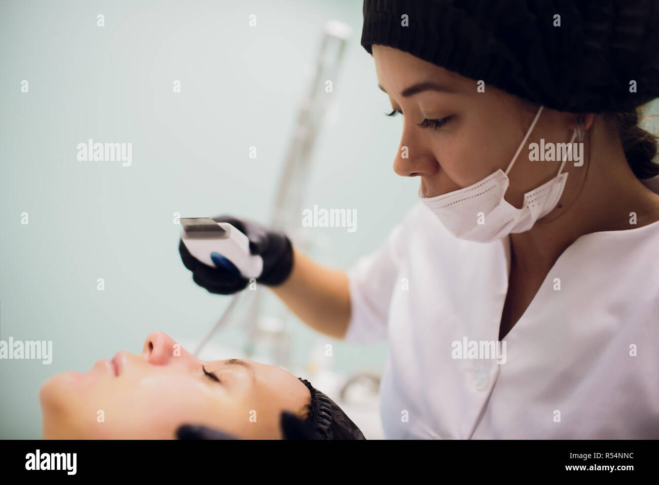Woman receiving cleansing therapy with professional ultrasonic equipment in cosmetology office