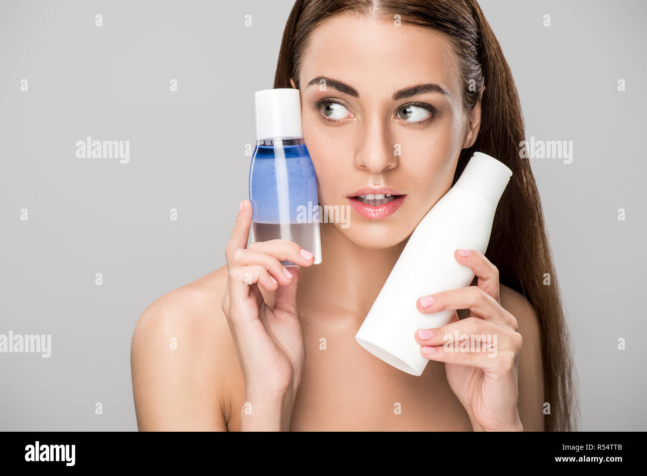 beautiful girl with perfect skin holding two bottles with makeup
