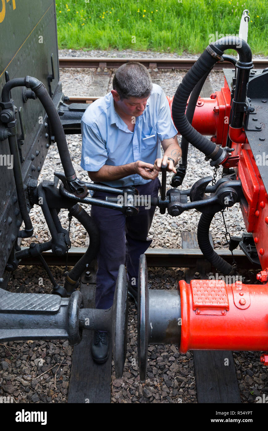Volunteer railway man / worker / staff coupling / uncoupling an engine from passenger carriages on the Isle of Wight steam Railway line. Station, Haven Street / Havenstreet, Ryde, UK. (98) Stock Photo