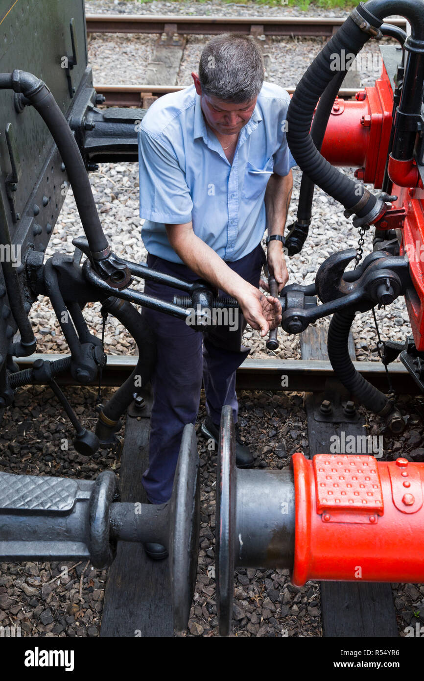 Volunteer railway man / worker / staff coupling / uncoupling an engine from passenger carriages on the Isle of Wight steam Railway line. Station, Haven Street / Havenstreet, Ryde, UK. (98) Stock Photo