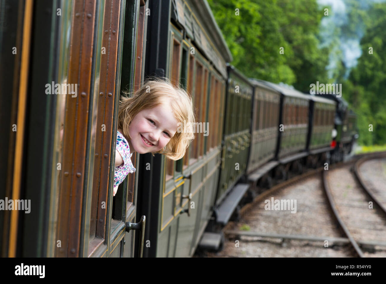 Passenger young girl aged 8 / eight years old, smiling & looking out of the window of a moving train carriage on the Isle of Wight steam Railway line. UK. (98) Stock Photo