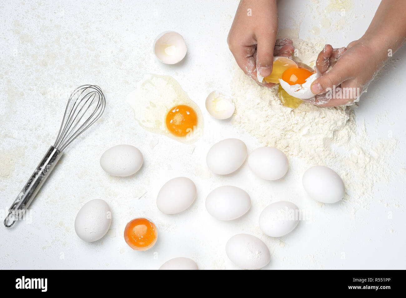 Basic ingredients into fresh pasta or dough with only  hands, eggs, flour,whisker on the white background. Flour on the work surface. Stock Photo