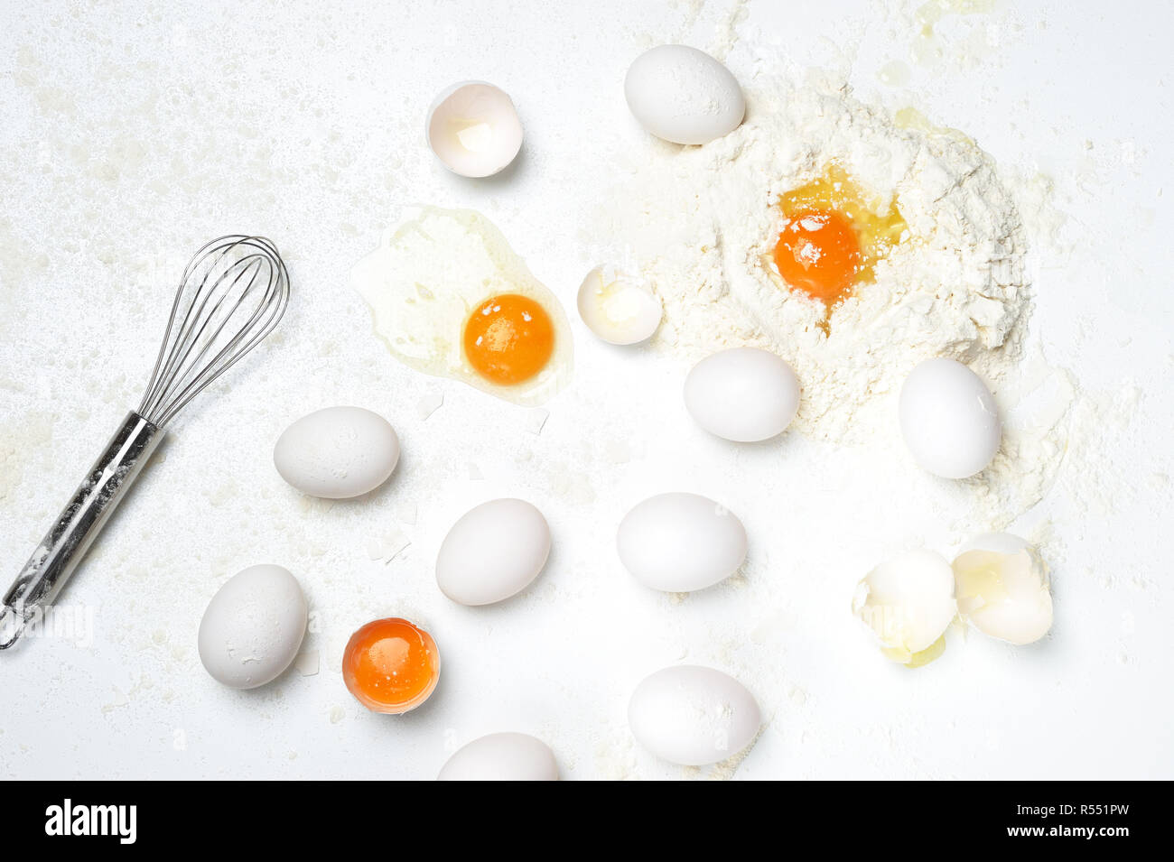 Basic ingredients into fresh pasta or dough with only  eggs, flour,whisker on the white background. Flour on the work surface. Stock Photo