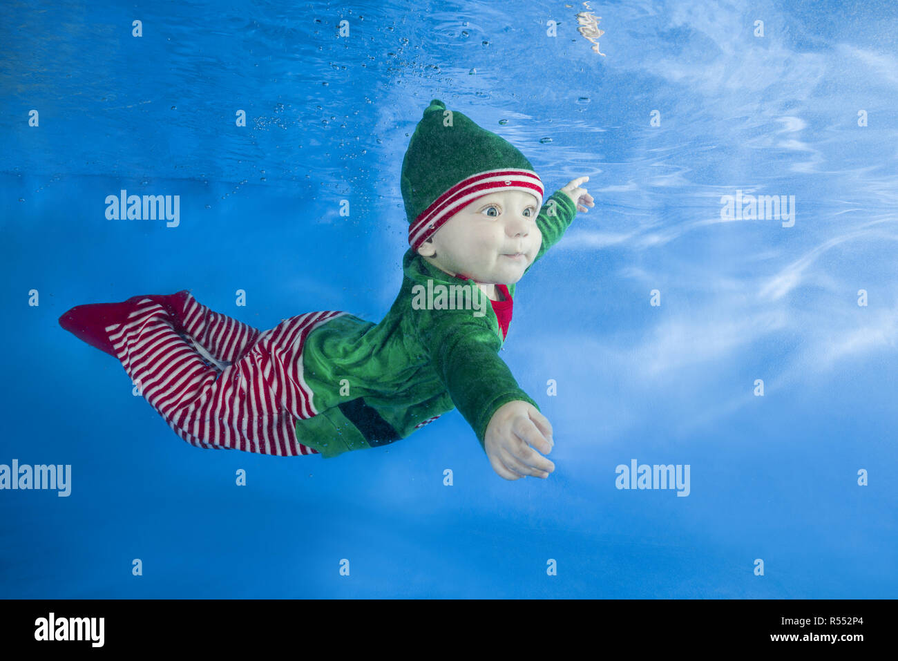 Little boy dressed as a gnome underwater on a blue water background.  Healthy family lifestyle and children water sports activity. Child development,  Stock Photo