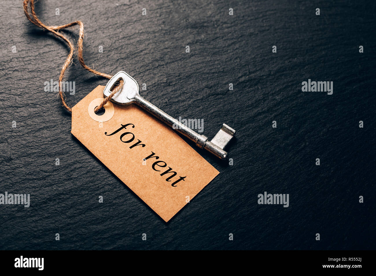 Old key with tag on black stone surface. Concept of real estate rent ...