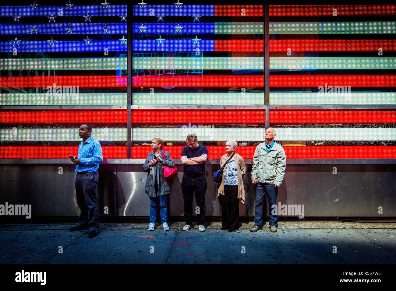 People waiting under the American flag on the wall of the US Military Recruitment center on Times Square. Stock Photo