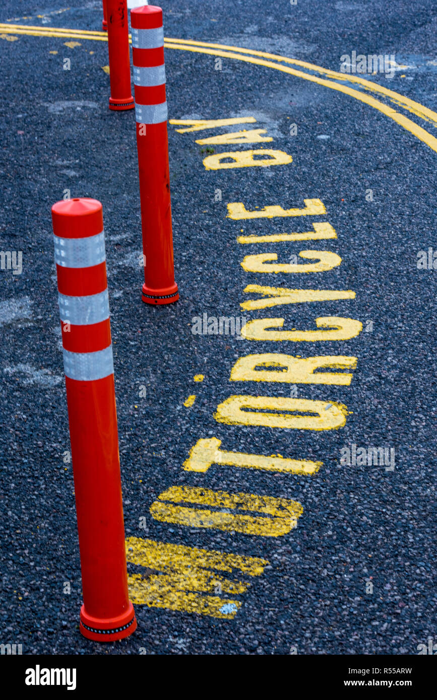 a parking space reserved for motorcycles with yellow road markings and orange and white marker bollards. Stock Photo