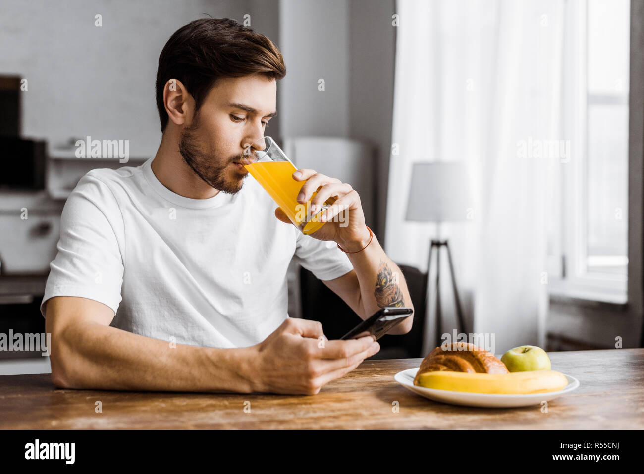 attractive young man using smartphone during breakfast at home Stock Photo