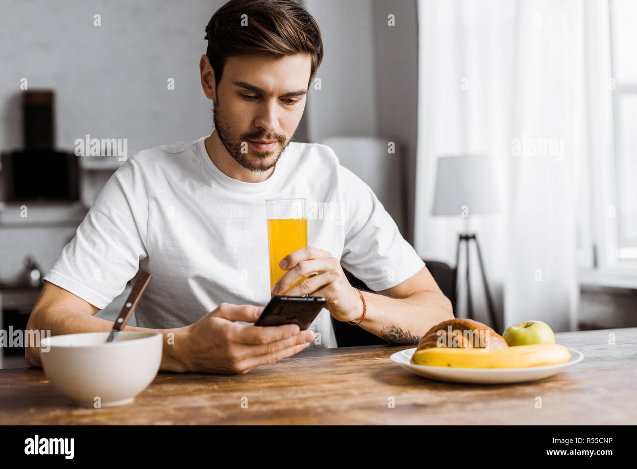 handsome young man using smartphone during breakfast at home Stock Photo