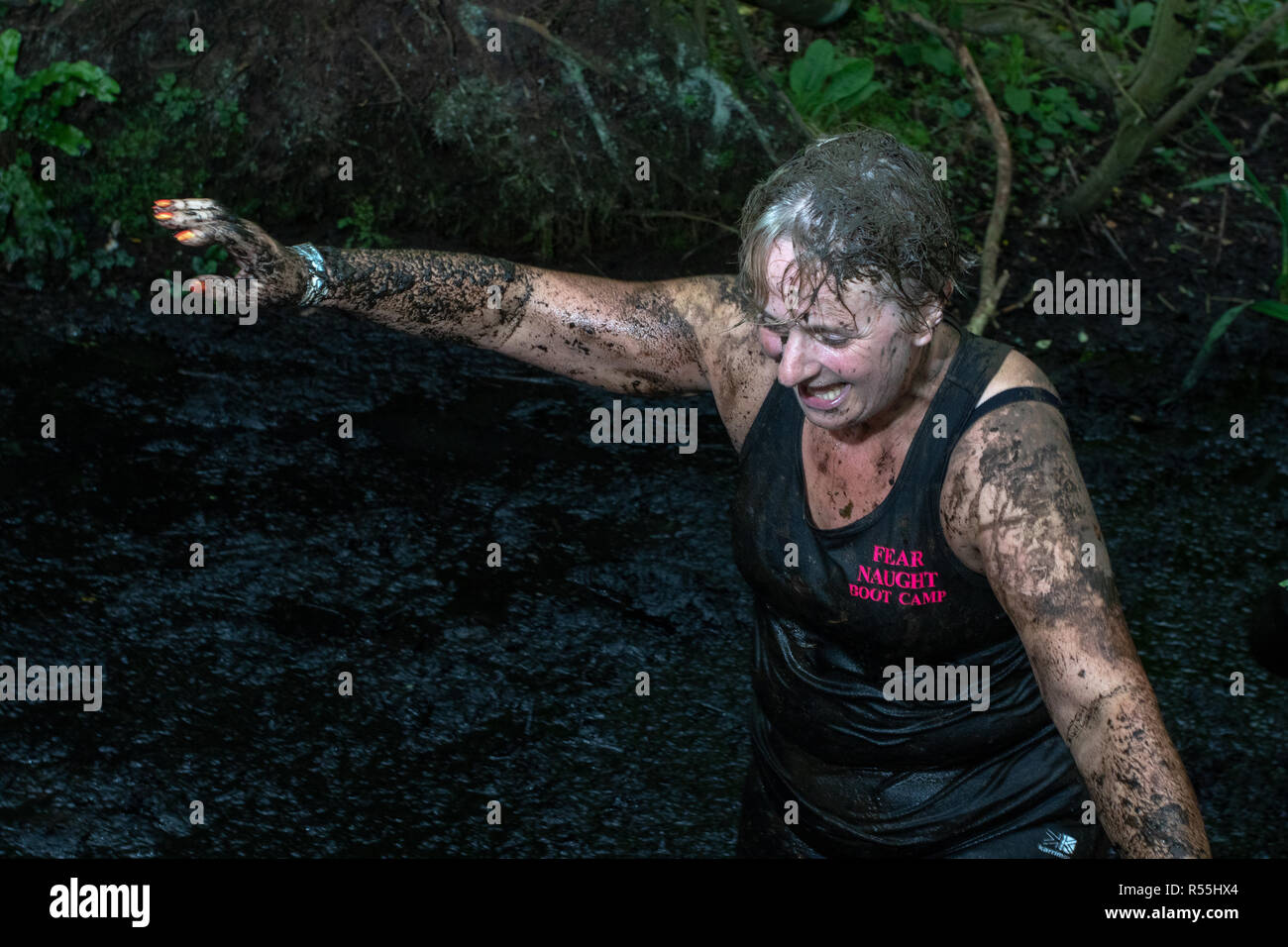 Mud covered woman wading through more mud Stock Photo