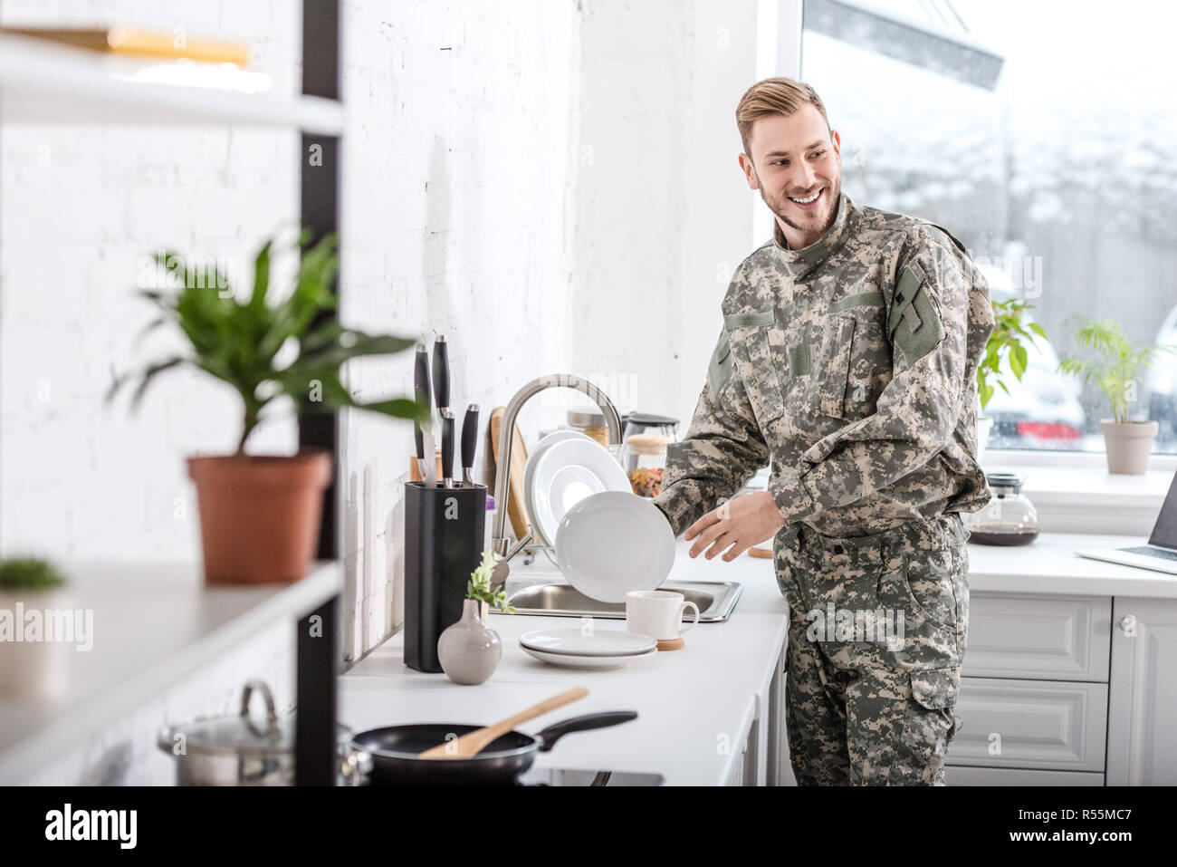 smiling army soldier cleaning dishes in kitchen Stock Photo Alamy