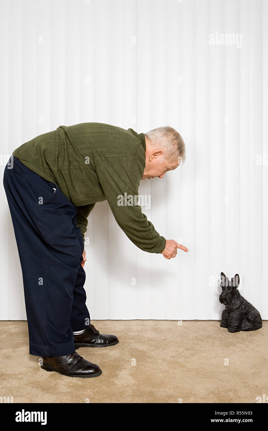 Elderly man pointing at dog ornament Stock Photo