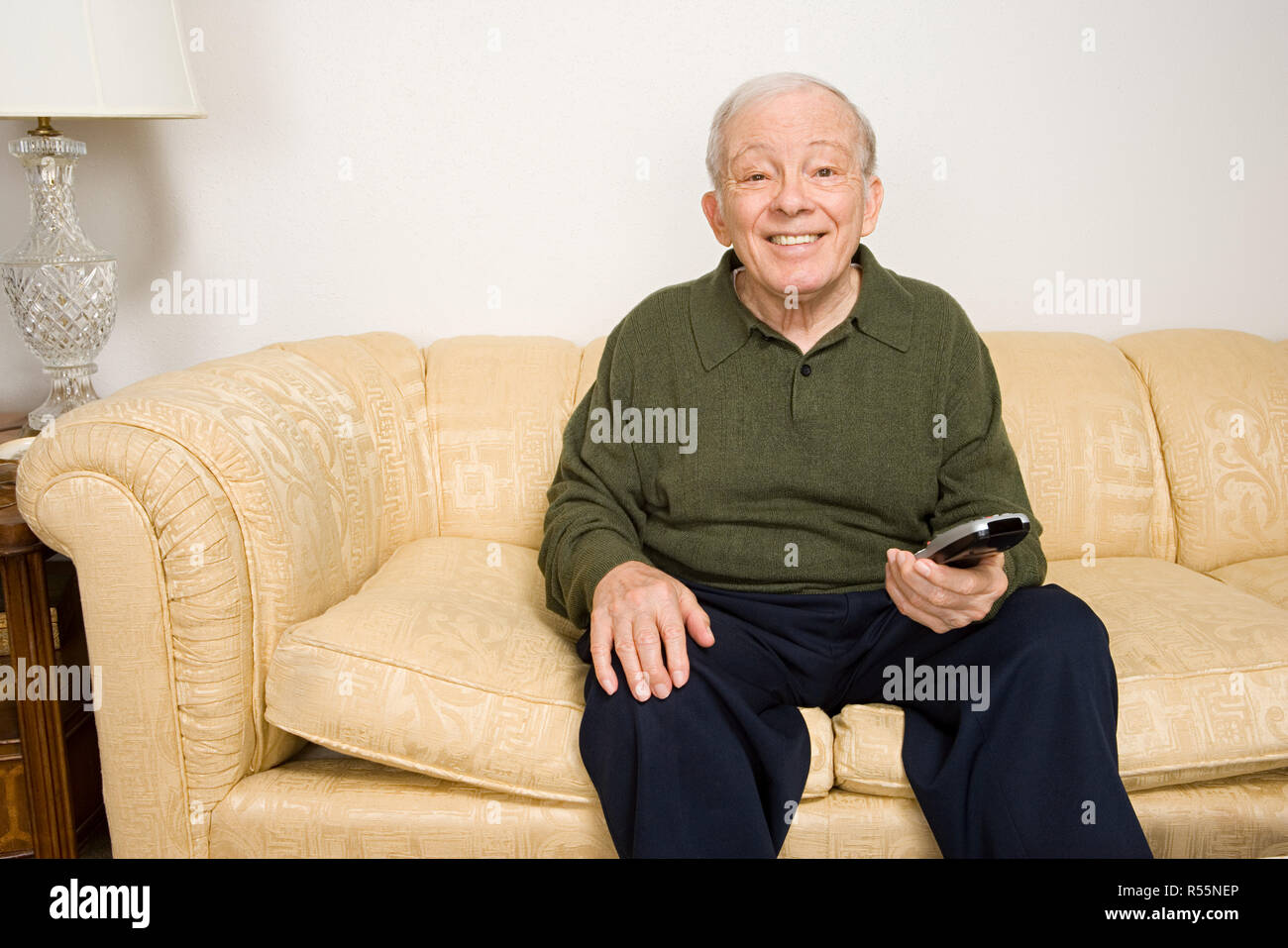 Elderly man on sofa with remote control Stock Photo