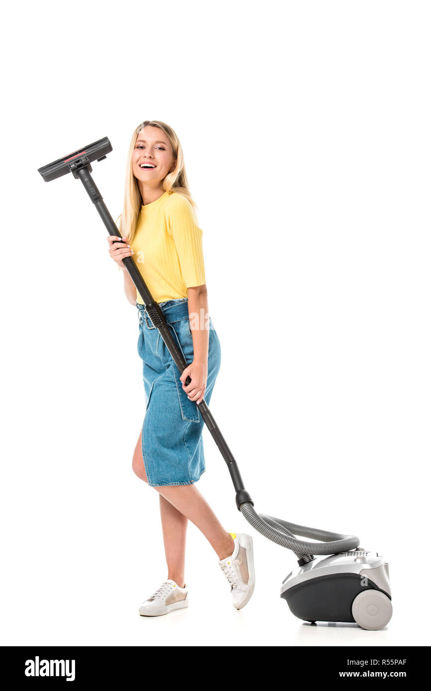 attractive young woman holding vacuum cleaner and smiling at camera