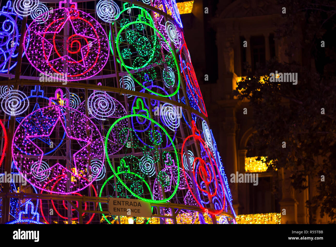 A part of modern christmas tree with led lights at night, building at