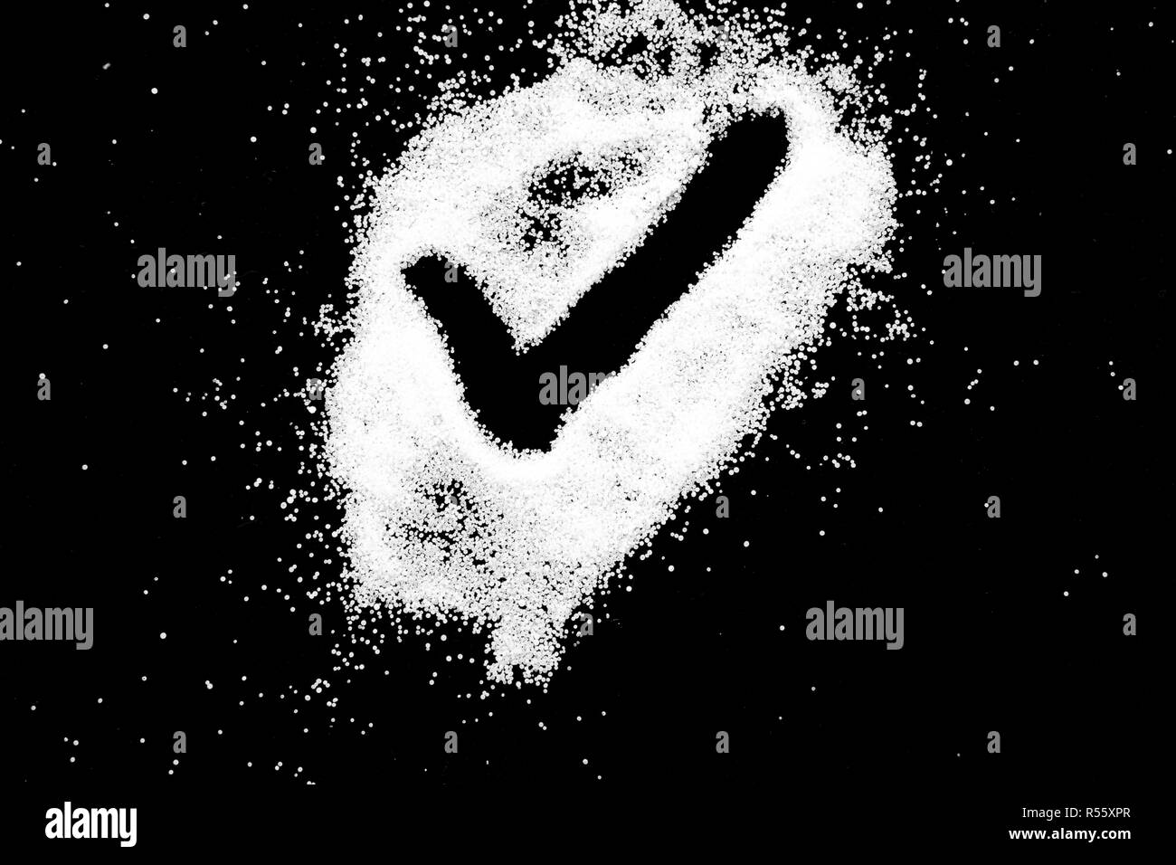 Checking mark symbol drawing by finger on white snow salt powder spot cloud in center on black background. Tick concept with place for text. Copy space. Stock Photo