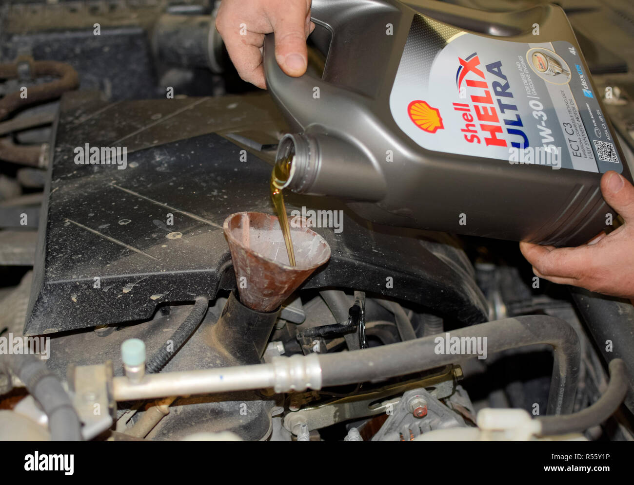 Oil change in the engine of the car. Filling the oil through the funnel. Car maintenance station. Stock Photo