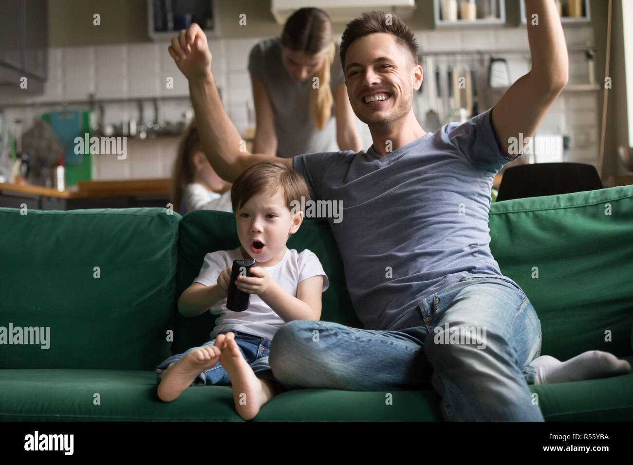 Son with father watching football on TV together Stock Photo