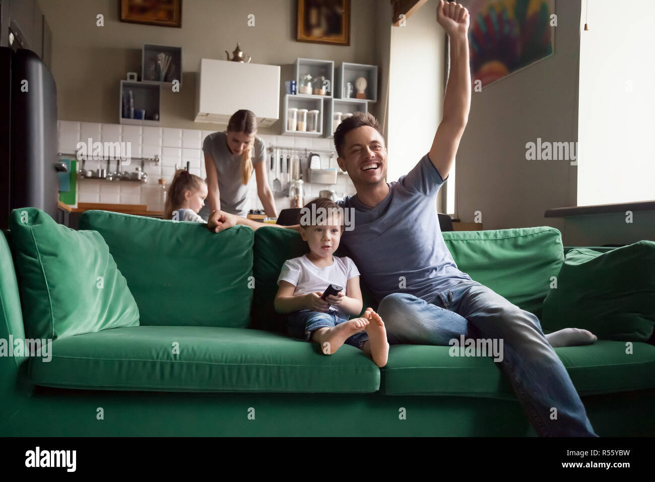 Son with father watching soccer on TV together Stock Photo