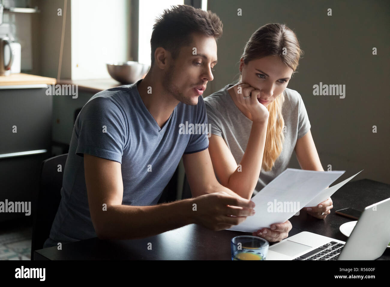 Serious young couple checking documents with using laptop Stock Photo