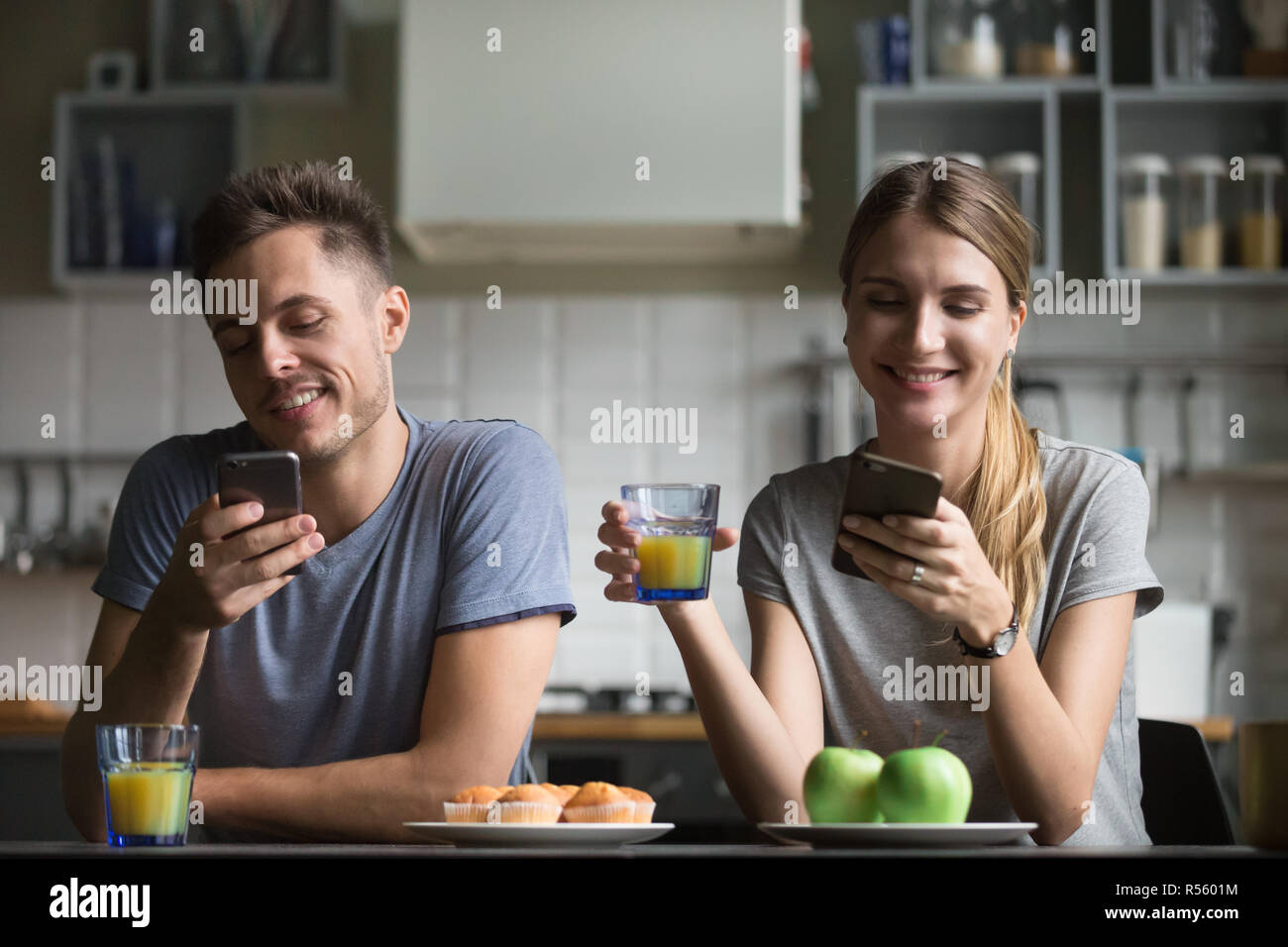 Happy young couple using smartphones during breakfast Stock Photo