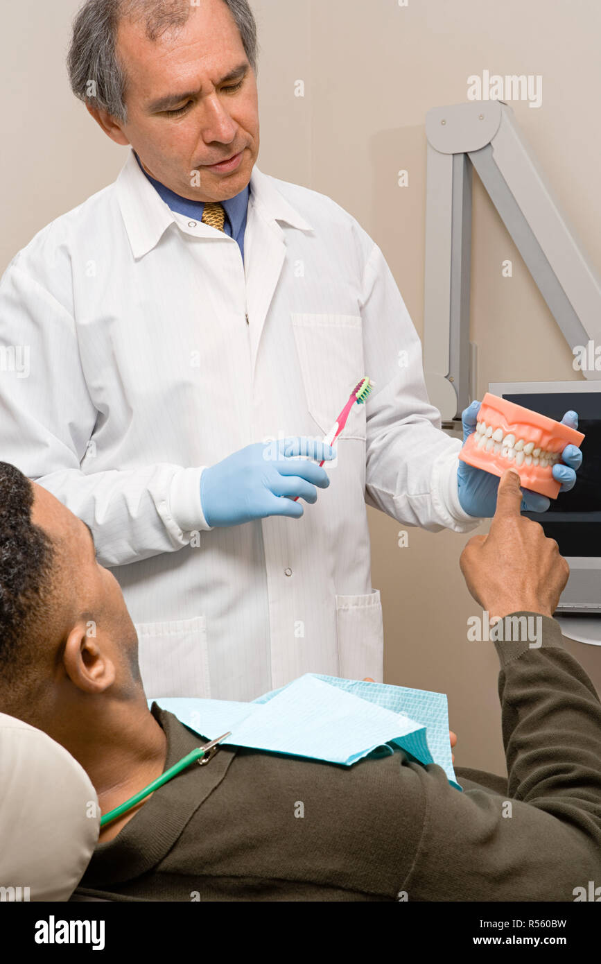 Dentist showing patient how to clean teeth Stock Photo Alamy