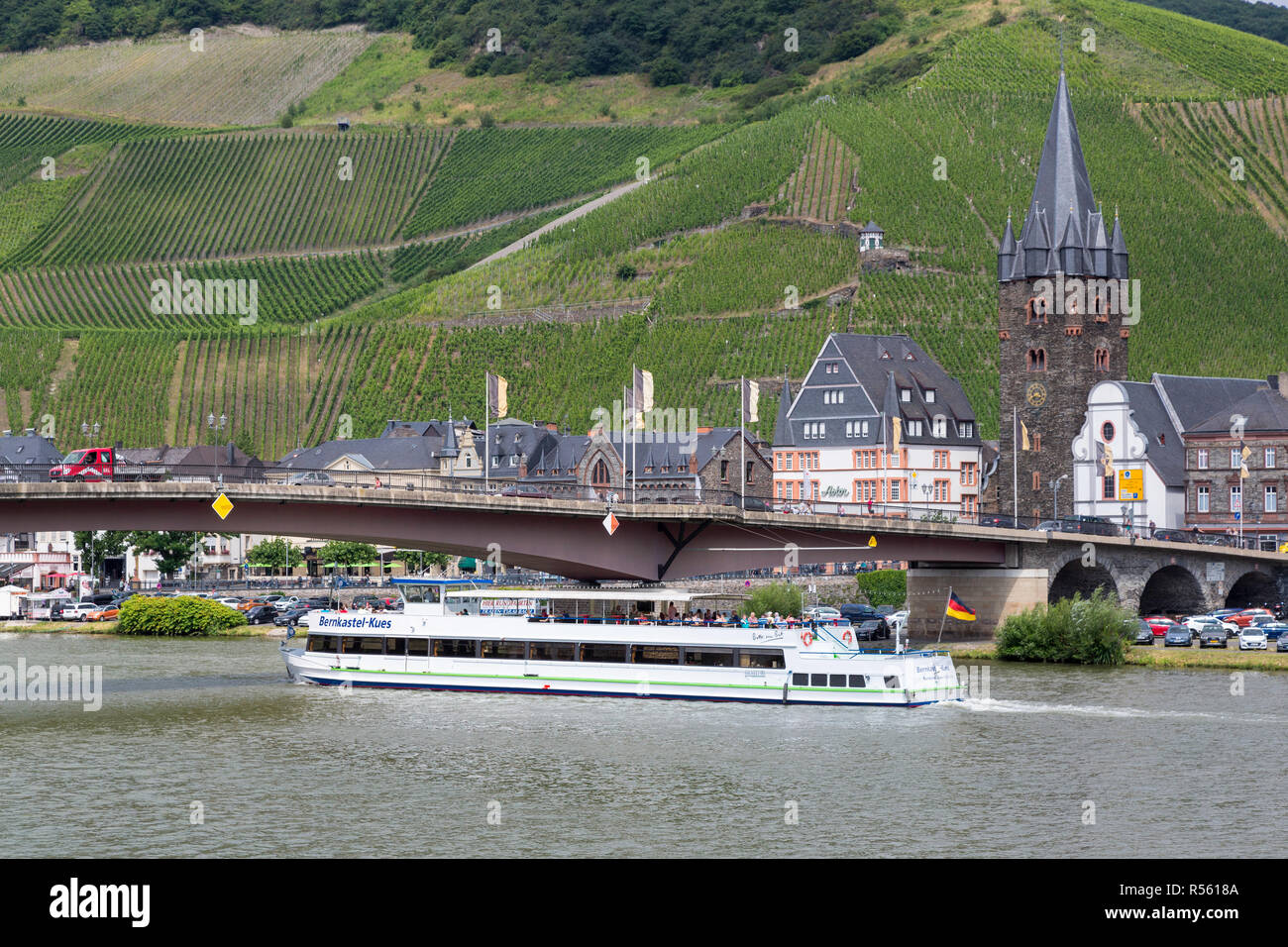 Bernkastel, Germany.  A Tourist River Cruise Boat on the Moselle.  St. Michael's Church and Medieval Tower on right. Stock Photo