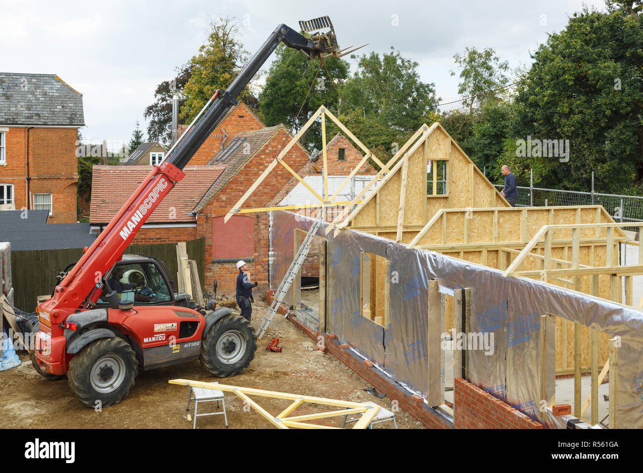Buckingham, UK - October 13, 2016. Heavy machinery lifts a roof truss into place on an extension to a period house. The extension is of timber frame c Stock Photo
