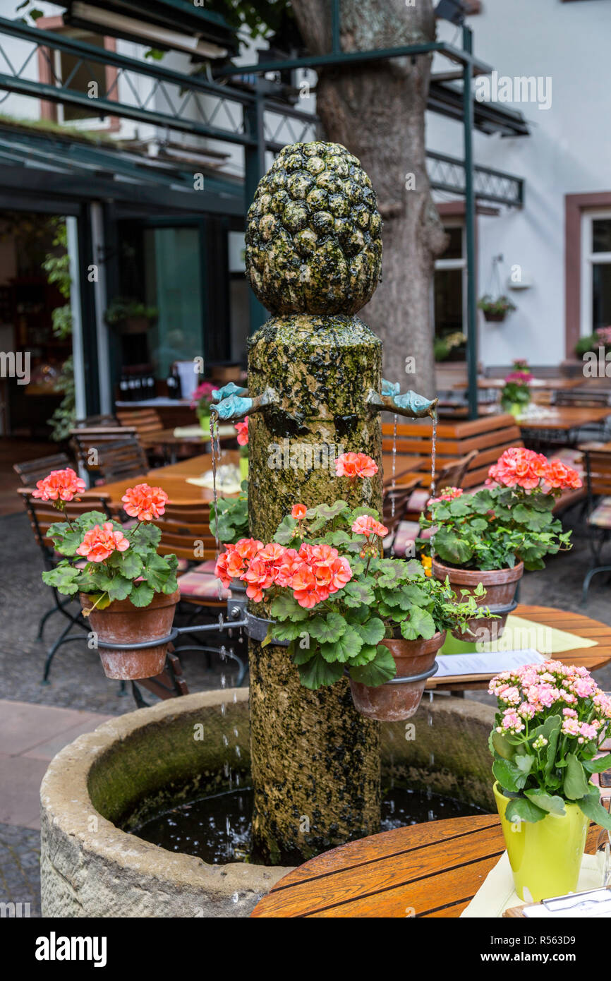 Rudesheim, Hesse, Germany.  Pineapple Fountain and Flower Pots in a Restaurant Courtyard. Stock Photo