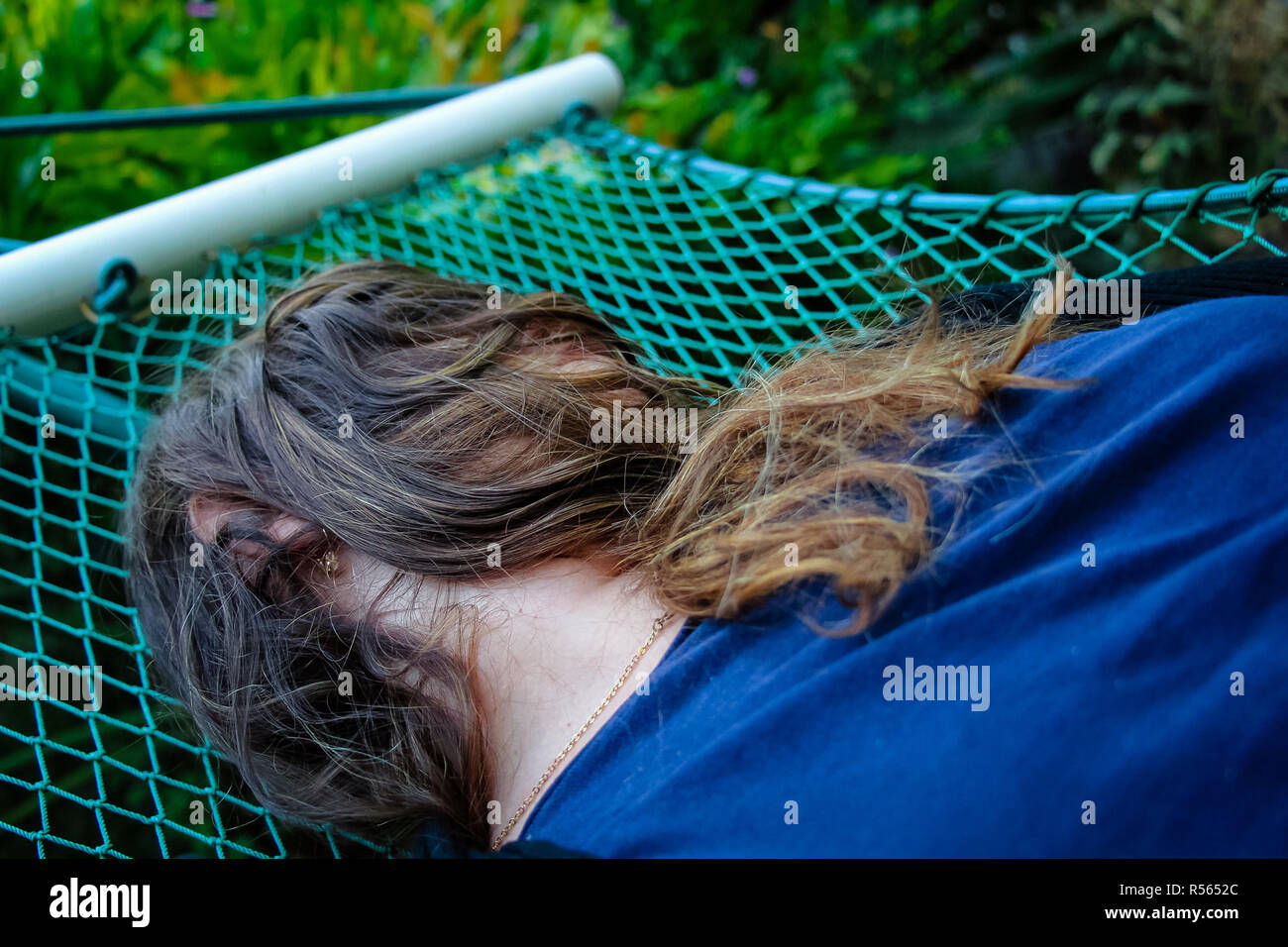 Woman laying down on a hammock and her face covered by her hairs Stock Photo Alamy