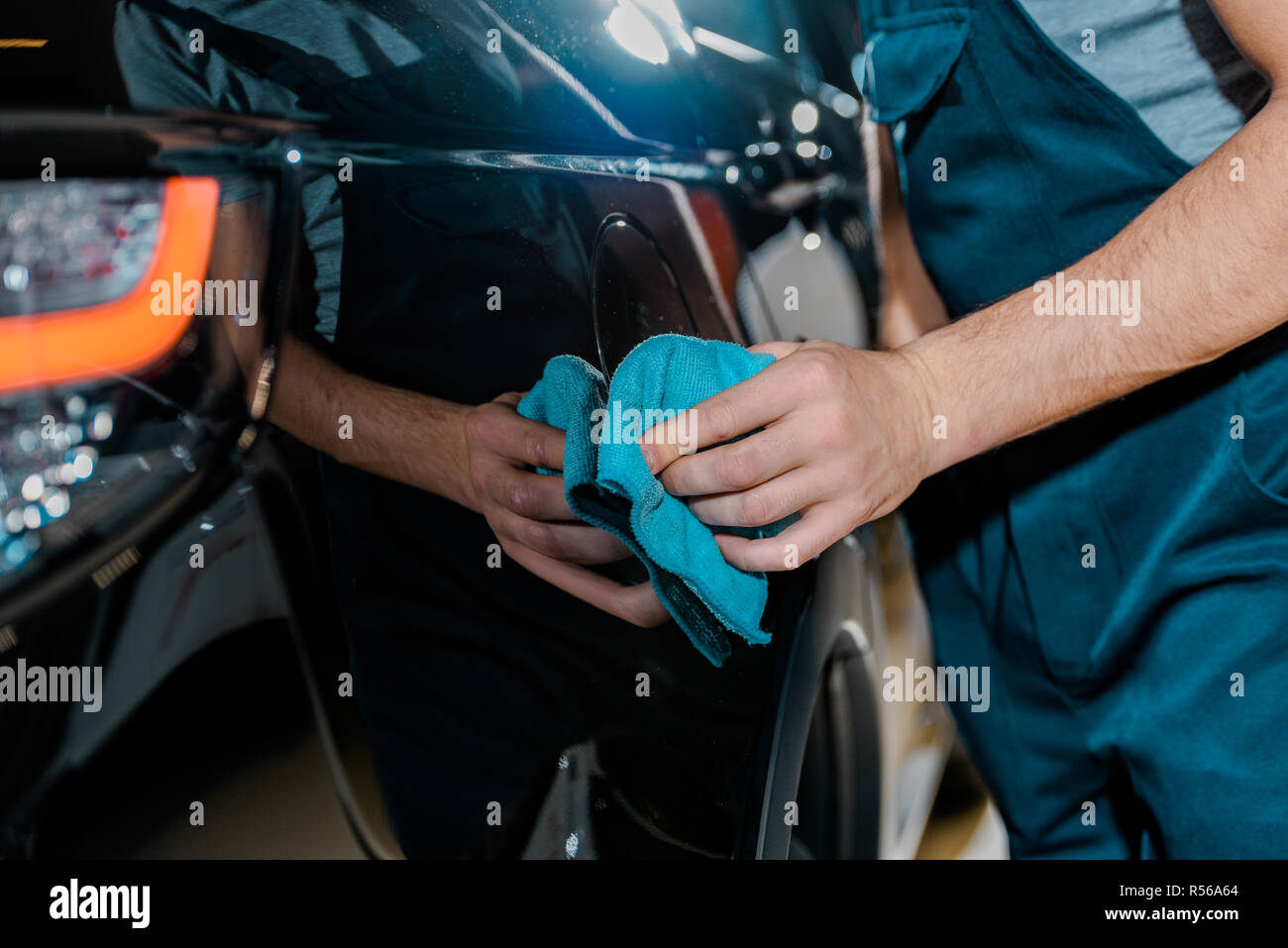 cropped shot of auto mechanic cleaning car with rag at auto repair shop Stock Photo