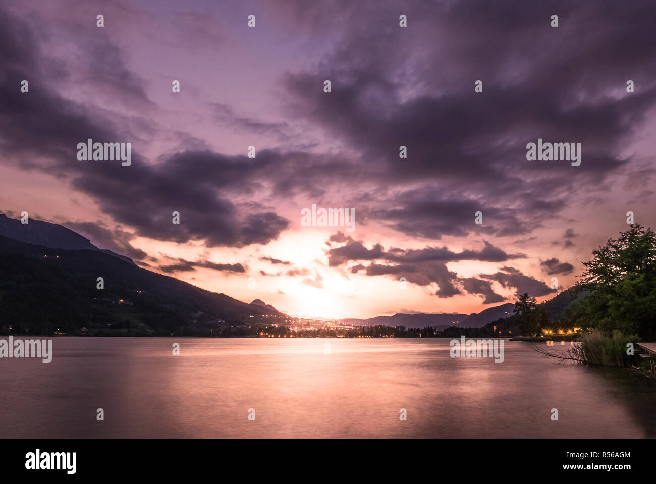 Dramatic sunset cloudscape over mountain lake, warm Stock Photo