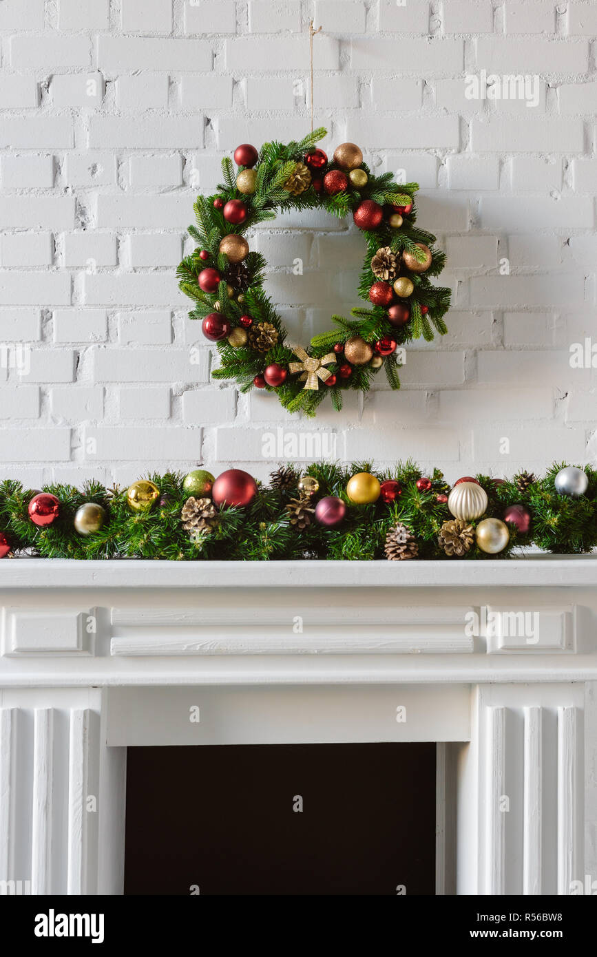 festive christmas wreath over fireplace mantel with white brick wall
