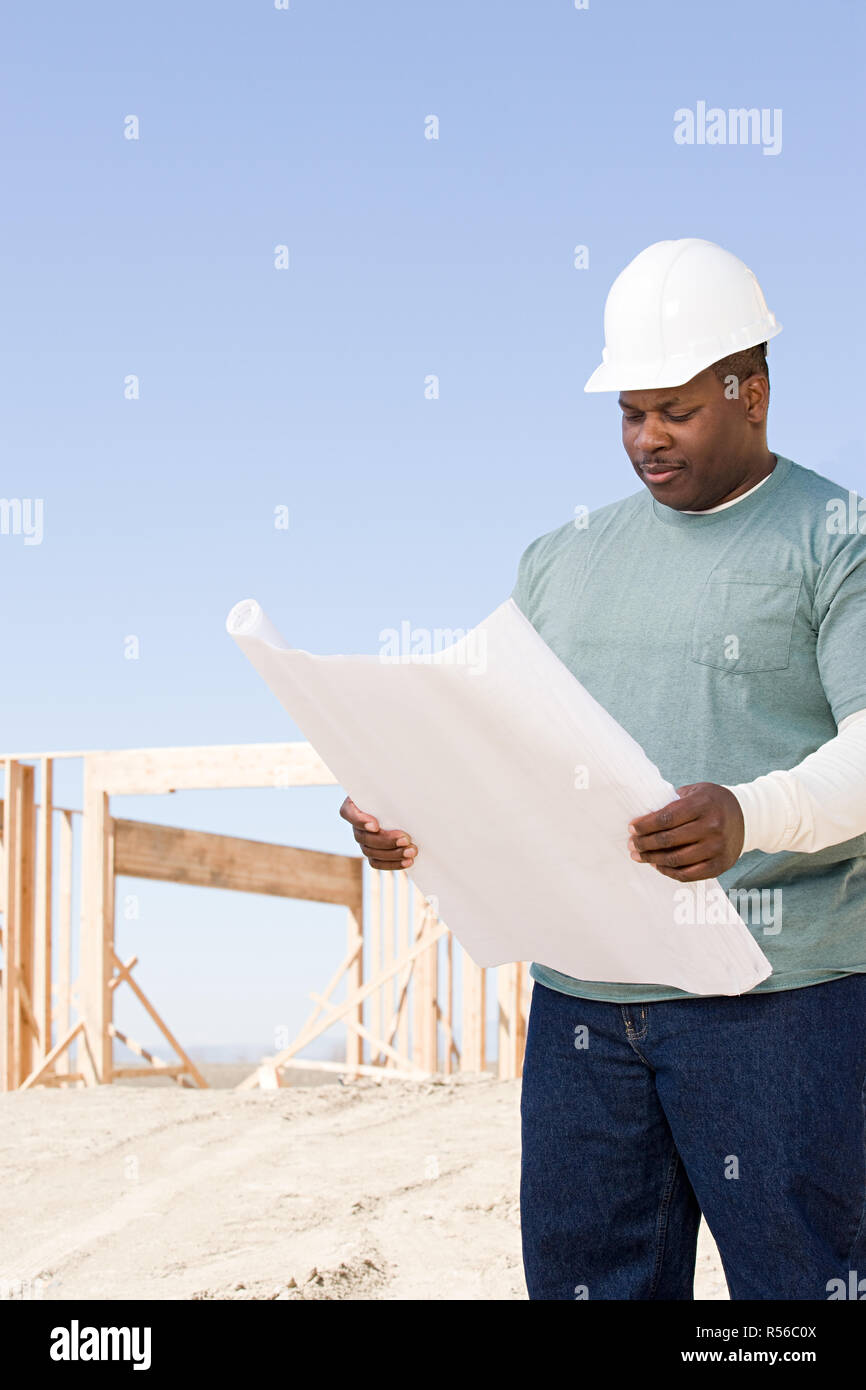 A builder holding a blueprint Stock Photo