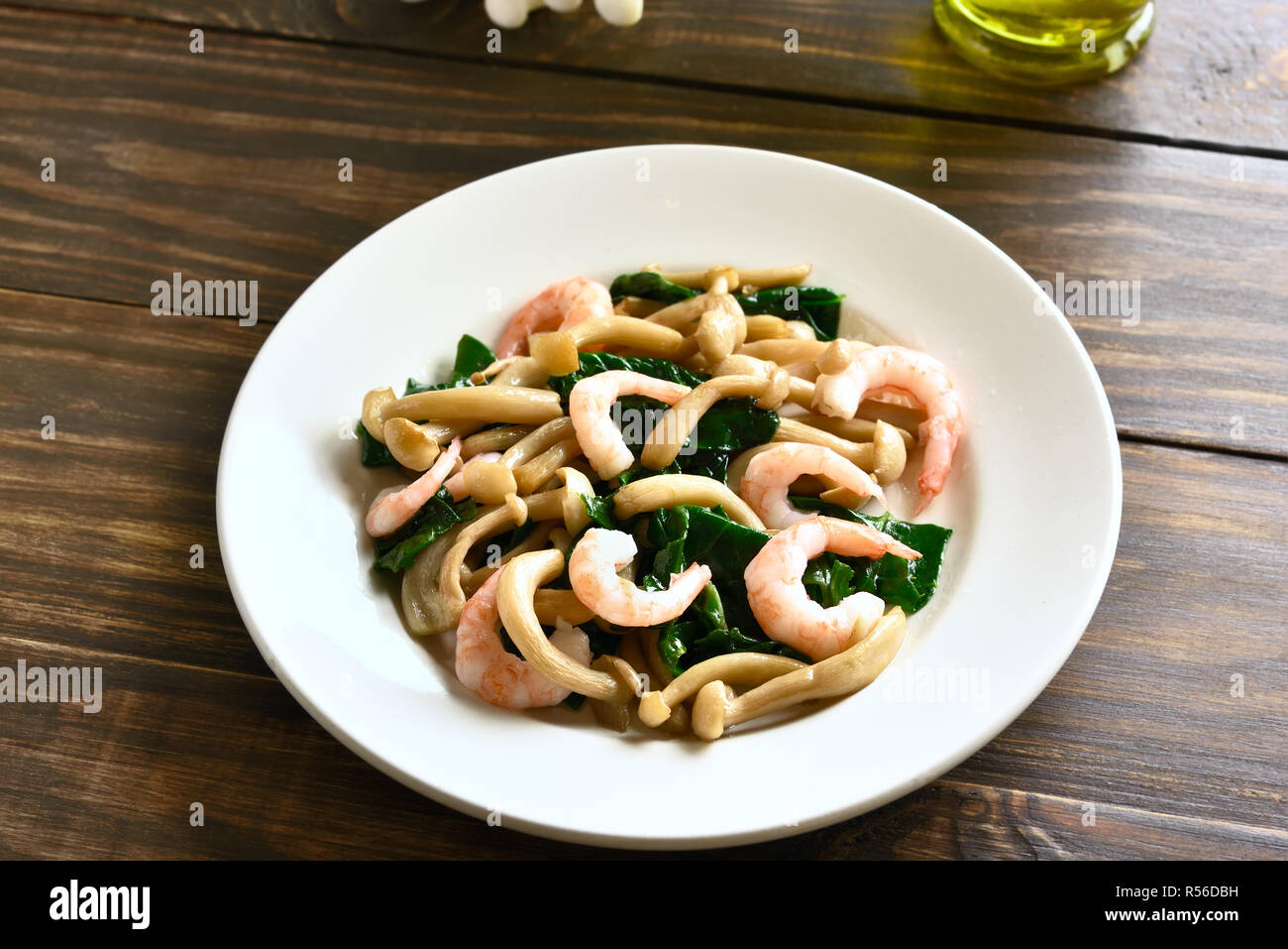 White beech mushrooms with leaves of spinach and shrimps on wooden table Stock Photo