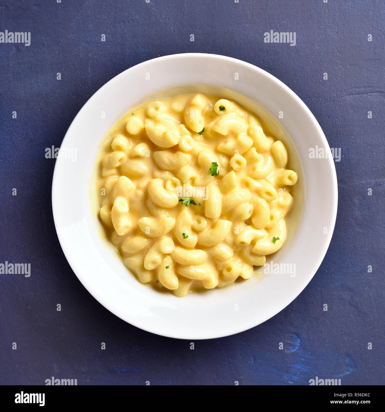 Macaroni and cheese in white bowl on blue stone background. Top view, flat lay Stock Photo