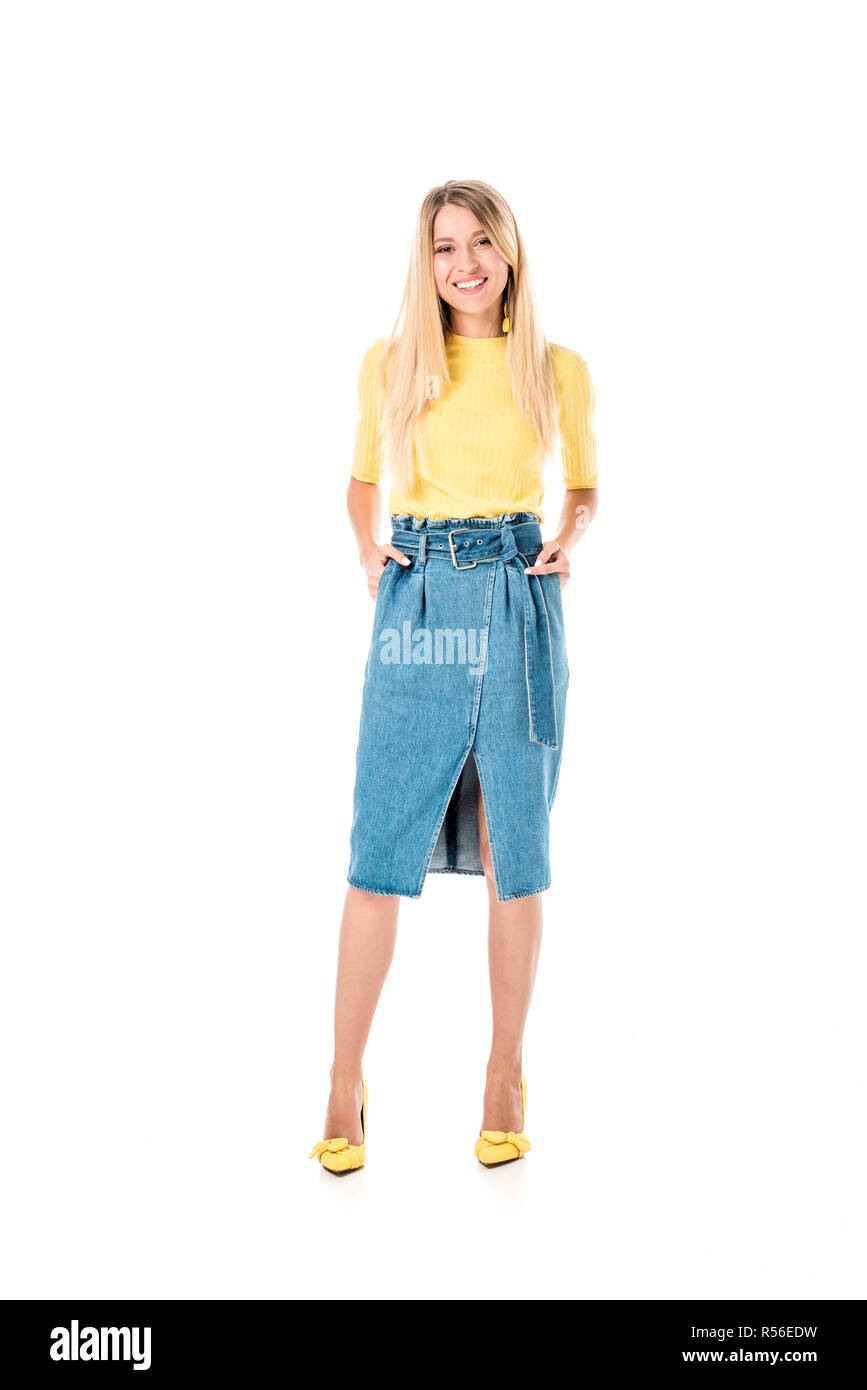 smiling attractive woman standing in yellow shirt and denim skirt