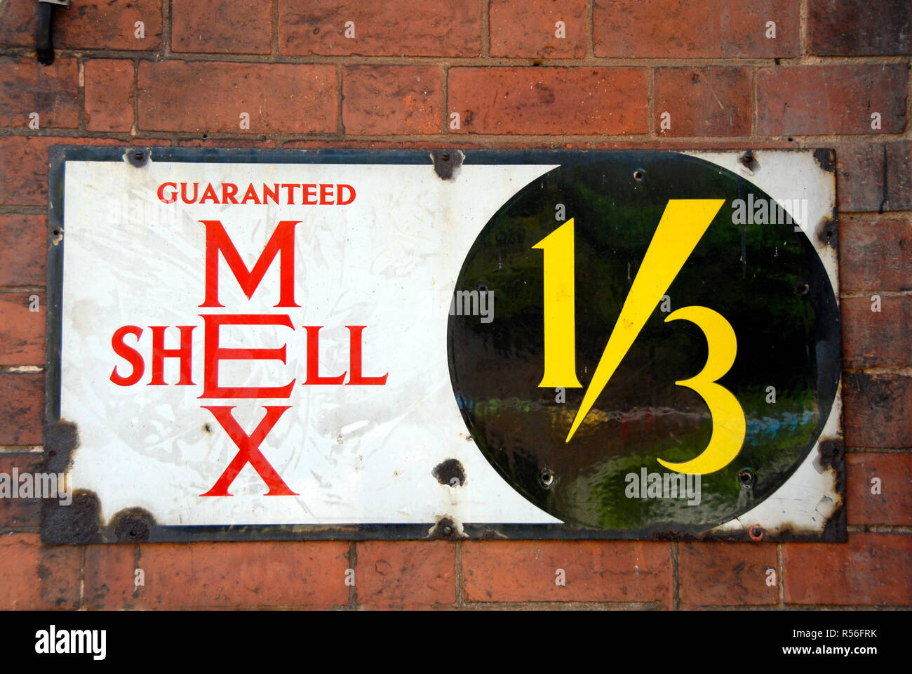 Old metal advertising panel for Shell Mex, fixed to brick wall, at a time when gasoline (petrol) was priced at one shilling and three pence per gallon Stock Photo