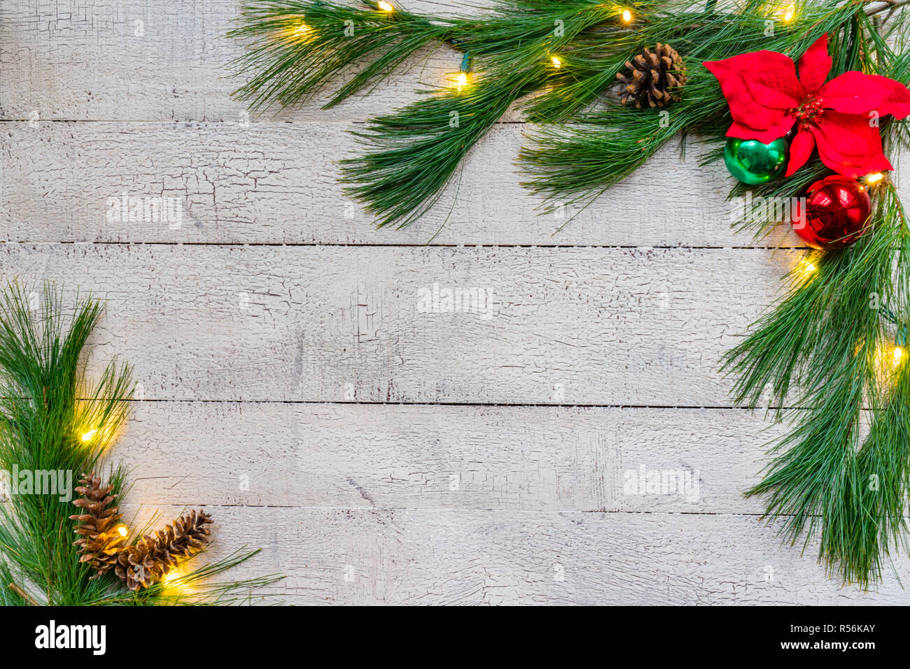 Christmas background with spruce greens, ornaments and lights on weathered white pine boards Stock Photo